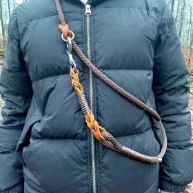 Mobile Preview: Person mit umhängender Hundeleine aus Tau espresso braun, Leder cognac braun mit Flechtungen und Beschlägen edelstahl im Wald